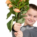 Eight years old boy presenting flowers, perhaps he is trying to say sorry or its Mothers Day